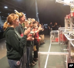 Student competitors watch a match between the soccer-ball kicking robots that they created.