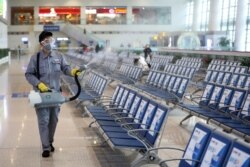 FILE - A worker in protective mask disinfects a waiting hall following the outbreak of a new coronavirus at the Nanjing Railway Station, in Nanjing, Jiangsu province, China, Jan. 27, 2020.
