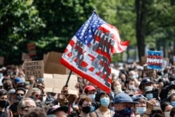 A protester waves an American flag with a message that reads "CAN'T BREATHE" during a memorial for George Floyd at Cadman Plaza Park in the Brooklyn borough of New York, on June 4, 2020.