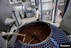 FILE - A worker stands beside a container of roasted coffee beans in a factory in Havana, Cuba, April 7, 2011.