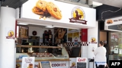 A woman (R) waits for her order outside a small shop on the first day of the easing of restrictions in Wellington, New Zealand, April 28, 2020, following the COVID-19 coronavirus outbreak.