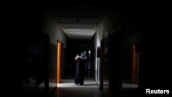 A Palestinian woman carries her sick child as she walks through the corridor at Durra hospital in Gaza City, Feb. 6, 2018. 