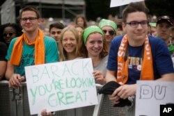 People hold posters to support U.S. President Barack Obama as they watch a discussion event on democracy and global responsibility at a Protestant conference in Berlin, Germany, May 25, 2017.