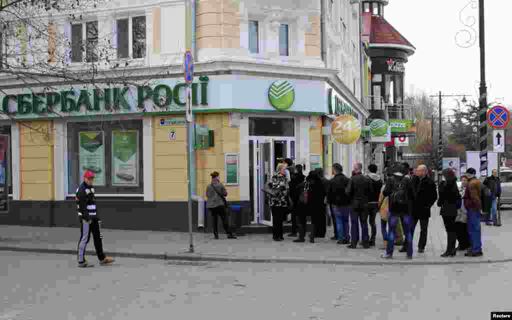 People stand in line as they wait to enter a branch of the Sberbank of Russia bank in the Crimean city of Simferopol, April 4, 2014.