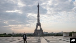 FILE - A man wears a mask to protect against the spread of the coronavirus as he walks along the Trocadero square close to the Eiffel Tower in Paris, April 24, 2020.