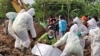 A mortuary team in full hazmat suits lowers the casket of a COVID-19 victim at a special cemetery in TPU Rorotan, north Jakarta, Indonesia, July 8, 2021. Some 200-400 bodies get buried there per day. (Indra Yoga/VOA Indonesian)