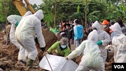 A mortuary team in full hazmat suits lowers the casket of a COVID-19 victim at a special cemetery in TPU Rorotan, north Jakarta, Indonesia, July 8, 2021. Some 200-400 bodies get buried there per day. (Indra Yoga/VOA Indonesian)