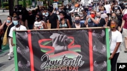 FILE - Demonstrators march through downtown Orlando, Fla., during a Juneteenth event, June 19, 2020, This year's swift approval of Juneteenth as a federal holiday sent many states hustling to figure out how to observe the event.