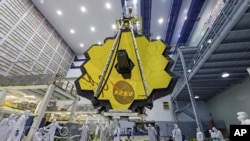 En esta fotografía de 2017 difundida por la NASA, varios técnicos elevan el espejo ensamblado del Telescopio Espacial James Webb.