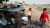 A woman cooks rice by a railway track in Phnom Penh, March 19, 2013. 
