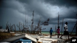 People walk next to a shattered and water-filled coffin that lies exposed to the elements in the aftermath of Hurricane Dorian, at the cemetery in Mclean's Town, Grand Bahama, Bahamas, Sept. 13, 2019. 