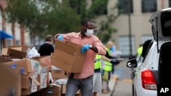 Volunteers load food into recipients cars at a food distribution point for people economically impacted by the coronavirus pandemic, organized by New Orleans City Councilman Jay Banks, in New Orleans, April 29, 2020.