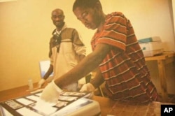 Staff at the International Library of African Music study negatives of photographs taken by Hugh Tracey during one of his fieldtrips