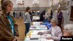 FILE - Election workers assist voters at Maryland Avenue Montessori School during Wisconsin's Supreme Court election in Milwaukee, April 4, 2023. 