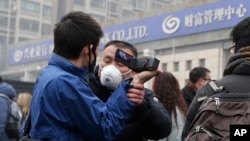 FILE - A plainclothes policeman grabs the hand of a foreign journalist as he prevents him from filming the supporters of rights lawyer Pu Zhiqiang's gathering near the Beijing Second Intermediate People's Court in Beijing, Dec. 14, 2015. 