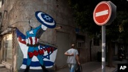 Un hombre en Tel Aviv pasa junto a un graffiti recién pintado de Joe Biden que representa al presidente de EEUU como un superhéroe defendiendo a Israel el lunes 30 de octubre de 2023.