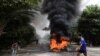 Pengunjuk rasa antikudeta melewati ban yang terbakar setelah para aktivis melancarkan "mogok sampah" untuk menentang pemerintahan militer di Yangon, Myanmar, 30 Maret 2021. (Foto: Reuters) 