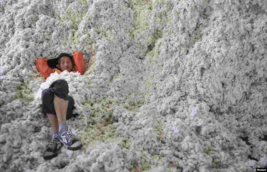 Seorang pekerja beristirahat dan bersandar pada tumpukan kapas di sebuah pabrik pengusaha kapas di Provinsi Wuhu, Anhui, China