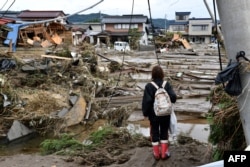 A woman looks at flood-damaged homes in Nagano on October 15, 2019, after Typhoon Hagibis hit Japan on October 12 unleashing high winds, torrential rain and triggered landslides and catastrophic flooding.