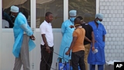 In this photo taken on March 29, 2014, medical personnel at the emergency entrance of a hospital receive suspected Ebola virus patients in Conakry, Guinea.