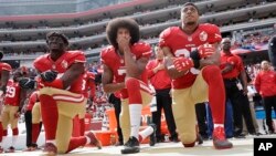 FILE - From left, San Francisco 49ers outside linebacker Eli Harold, quarterback Colin Kaepernick and safety Eric Reid kneel during the national anthem before an NFL football game against the Dallas Cowboys in Santa Clara, California, Oct. 2, 2016.