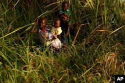 FILE - Children cross a swamp area to reach a registration area prior to food distribution carried out by the United Nations World Food Program (WFP) in Thonyor, Leer county, South Sudan, Feb. 25, 2017.
