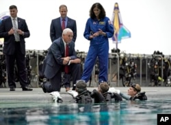 Vice President Mike Pence kneels as he listens to astronaut Suni Williams, right, talk with astronaut candidates in the pool at NASA's Johnson Space Center in Houston, Aug. 23, 2018.