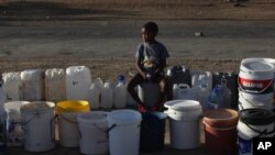 A boy keeps a spot in a queue for free water being transported in by the municipality, in Senekal, South Africa, Jan. 7, 2016.