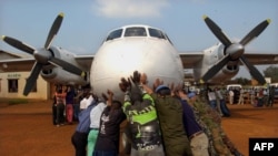 Des volontaires congolais poussent un avion de l'ONU le 25 juillet 2002