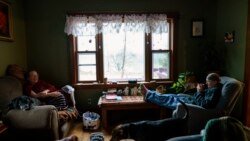 Caroline Clarin, right, and her wife, Sheril Raymond, sit in their living room with their dogs, Daisy, left, and Iorek, in Dalton, Minn., Oct. 27, 2021.