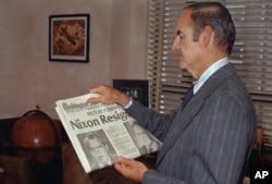 Sen. George McGovern (D-SD) reads the newspaper headline of President Nixon's resignation, Aug. 7, 1974.