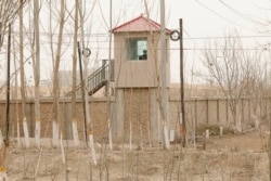 FILE - A security person watches from a guard tower around a detention facility in Yarkent County in northwestern China's Xinjiang Uyghur Autonomous Region, March 21, 2021.