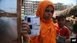 A Rohingya woman displays family members' identity cards issued by United Nations High Commissioner for Refugees (UNHCR) at their makeshift camp on the outskirts of Jammu, India, March 9,2021.
