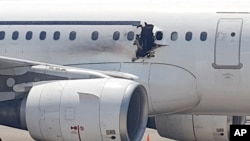 A gaping hole is visible in the side of a plane operated by Daallo Airlines as it sits on the runway of the airport in Mogadishu, Somalia, Feb. 2, 2016. 