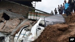 Rescuers inspect the damage in a neighborhood hit by a landslide in the village of Banaran, Ponorogo, East Java, Indonesia, April 1, 2017. More than two dozen people were reported missing Saturday after the rain-triggered landslide struck a village on Indonesia's main island of Java. 