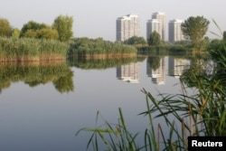 Blocks of apartments are reflected in one of the lakes inside Vacaresti wetlands, in Bucharest, Romania, July 29, 2016.