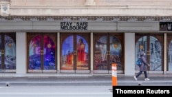 A woman walks on a mostly-empty city center street on the first day of a seven-day lockdown as the state of Victoria looks to curb the spread of COVID-19, in Melbourne, Australia, May 28, 2021. 
