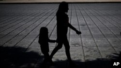 FILE - A woman and child walk during a march against human trafficking and slavery, on Paseo de la Reforma boulevard in Mexico City, Oct. 14, 2017. 