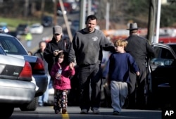FILE - Today’s high school students were young children when a shooter killed 20 children at Sandy Hook Elementary School in Newtown, Connecticut in 2012. In this photo, parents reunited with their children following the shooting at Sandy Hook Elementary School.