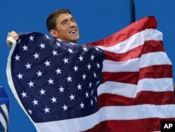 United States' Michael Phelps walks with his national flag during the medal ceremony for the men's 4 x 100-meter medley relay final during the swimming competitions at the 2016 Summer Olympics, Sunday, Aug. 14, 2016, in Rio de Janeiro, Brazil.