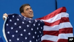 United States' Michael Phelps walks with his national flag during the medal ceremony for the men's 4 x 100-meter medley relay final during the swimming competitions at the 2016 Summer Olympics, Aug. 14, 2016, in Rio de Janeiro, Brazil.