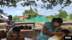 Lang Chanthoeun, 35, a villager in Kampong Thom province’s Krayea commune, looks after her daughter, who has been diagnosed with dengue fever, as she vomits while Lang Chanthoeun gives an interview to VOA, June 2019. (Sun Narin/VOA Khmer)