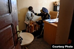 Police Maj. Honorine Munyole takes the statement of Giselle, 15, who was summoned to the police station by officers who caught the young man she said raped her two weeks earlier. (Photo by Mary F. Calvert/The Washington Times)
