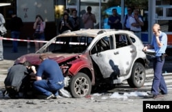 FILE - Investigators inspect a damaged car at the site where journalist Pavel Sheremet was killed by a car bomb in central Kiev, Ukraine, July 20, 2016.