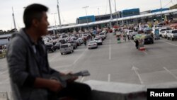 A man sits as cars queue up in multiple lines waiting to be inspected by U.S. border patrol officers to enter from Mexico into the U.S., at the San Ysidro port of entry, in Tijuana, Mexico, April 3, 2019. 