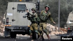 A stone is thrown at an Israeli soldier during clashes with Palestinians following a protest against the near-by Jewish settlement of Qadomem, in the West Bank village of Kofr Qadom near Nablus, Aug. 25, 2017.
