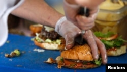 FILE - French burgers are prepared at 'Le Refectoire' food truck in Paris, Nov. 16, 2012.