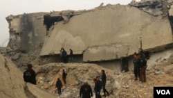 Civil defense members and other people inspect a damaged mosque after an airstrike on the village of al-Jinah, Aleppo province, in northwest Syria, March 17, 2017.