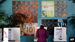 FILE - A woman votes at a polling station inside a coffee shop in Los Angeles, March 7,2017. The California secretary of state has again rejected a request for voter information from President Donald Trump's commission investigating alleged voter fraud.