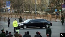 Security officials stand guard while a Mercedes limousine in a motorcade believed to be carrying North Korean leader Kim Jong Un passes along a street in Beijing, Wednesday, Jan. 9, 2019. 